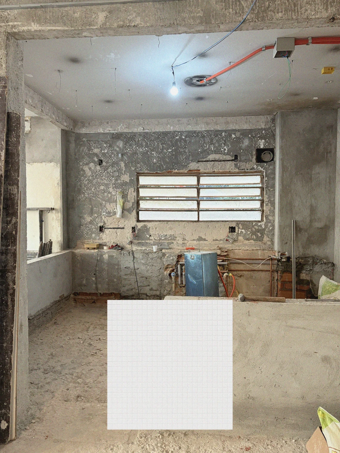 Fotografia de obra da cozinha em reforma no Apartamento Itacolomi com paredes descascadas e instalações expostas, sobreposta por amostra de pastilhas quadradas claras.