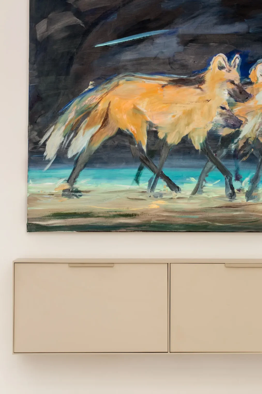 Detalhe de aparador suspenso em serralheria de chapa de aço com pintura creme, instalado sob uma tela com pintura de lobos-guará.