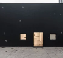 Fachada preta da Galeria Vermelho em São Paulo com intervenção gráfica de teclas de computador e porta central iluminada.